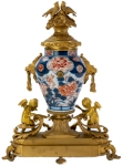 Stamp of Feldman International Auctions » Mobilier, Objets d'Art & Design / Furniture, Objets d'Art & Design Garniture de cheminée dans le style du XVIIIème siècle comprenant une pendule et deux candélabres, associés à des vases Imari. XIXème siècle